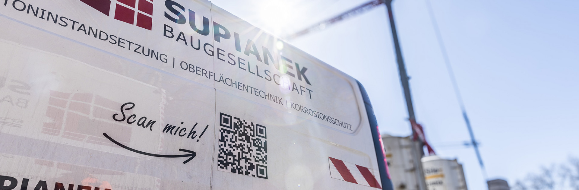 Ein weißer Transporter der Supianek Bau steht an einer Baustelle.